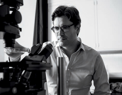 Mark Miskin next to lab equipment in black and white