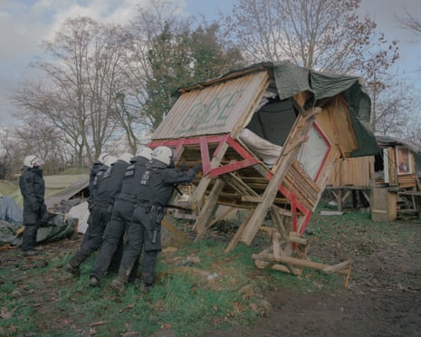 Police officers destroy a wooden house