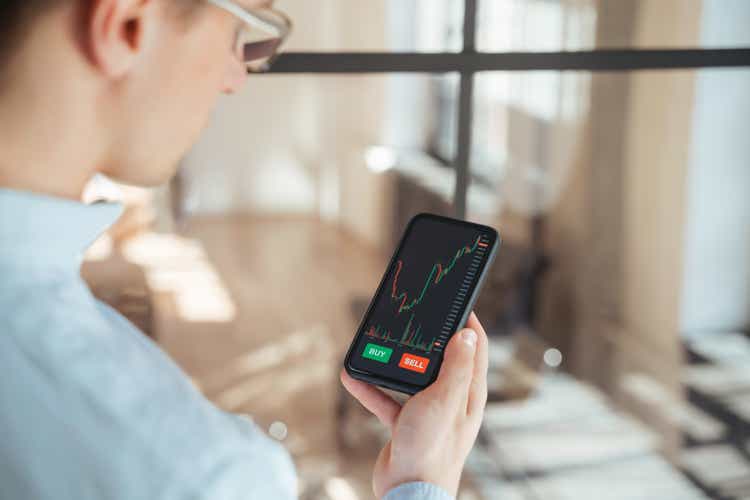 Cropped rare view of guy checking bitcoin price chart on digital stock exchange app on phone