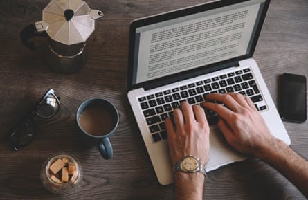 A man typing on his laptop at home while having a coffee from the coffee maker.