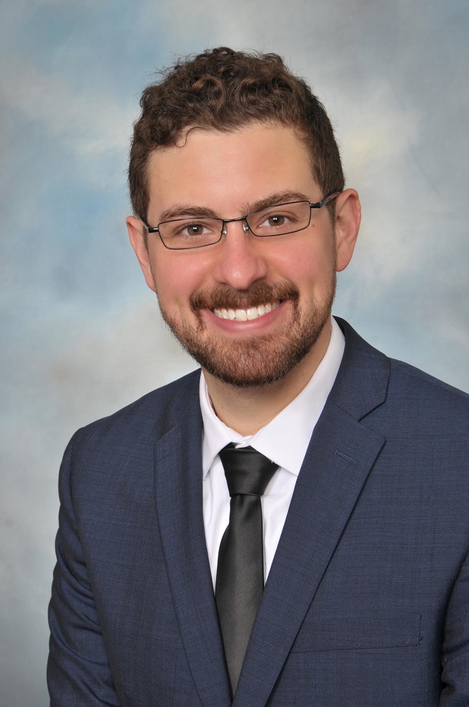 Matthew Stamm in front of a blue marbled background.