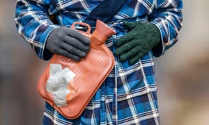 A person in dressing gown and gloves holding a water bottle.