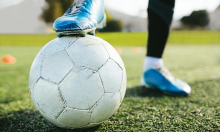 The foot of a football player, resting on a ball.