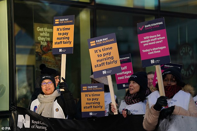 Striking nurses hold a banner and placards outside Queen Elizabeth hospital in Birmingham on February 6