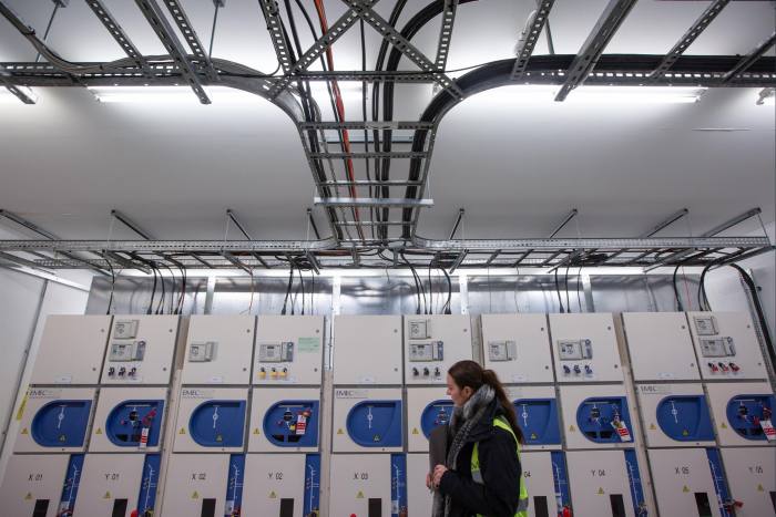 female employee looking at machines inside an electric power substation