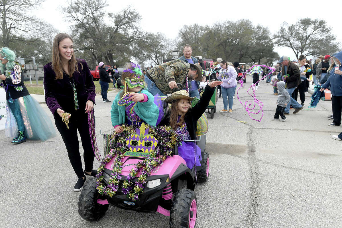 Sisters Genevieve (left) and Josephine Fruge toss beads to the crowd gathered for the Munchkin Parade during Mardi Gras on the Sabine Saturday in Orange. Photo made Saturday, February 11, 2023 Kim Brent/Beaumont Enterprise