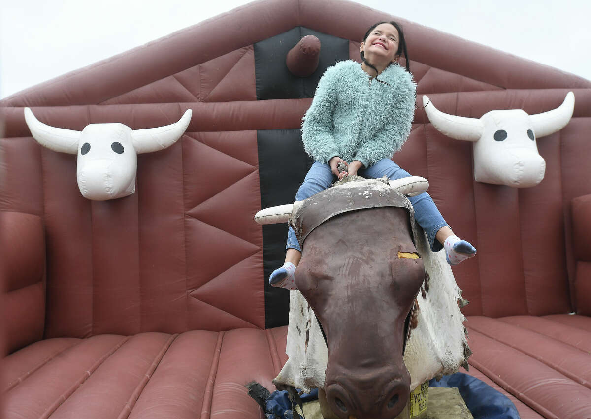 Zayda Diaz-Crawford laughs as she tries to hang on the mechanical bull ride during Mardi Gras on the Sabine Saturday in Orange. Photo made Saturday, February 11, 2023 Kim Brent/Beaumont Enterprise