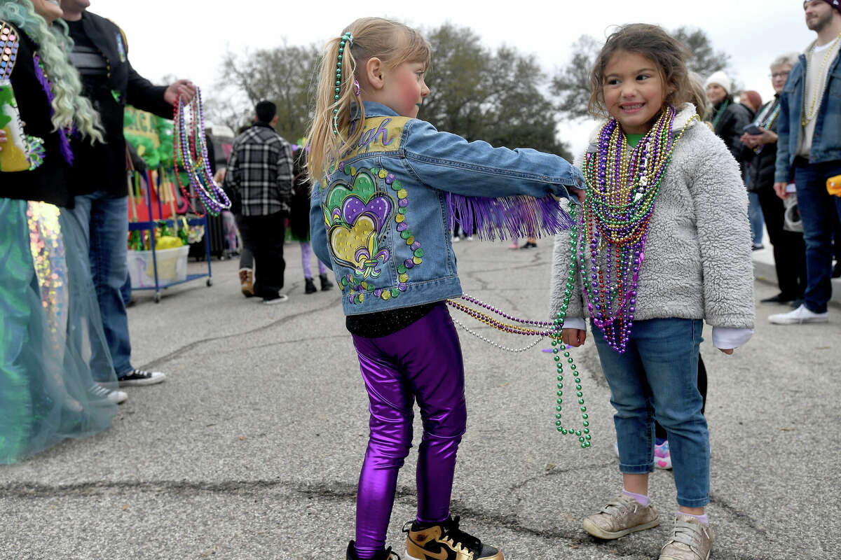 Brynleigh Stanley gives another strand of beads to a Munchkin Parade watcher during Mardi Gras on the Sabine Saturday in Orange. Photo made Saturday, February 11, 2023 Kim Brent/Beaumont Enterprise