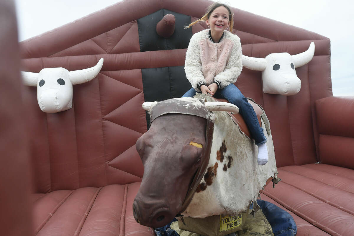 Ava Youngblood rides a mechanical bull in the kids' zone during Mardi Gras on the Sabine Saturday in Orange. Photo made Saturday, February 11, 2023 Kim Brent/Beaumont Enterprise