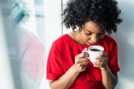 A woman standing by the window holding a cup of coffee