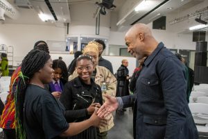 Eric Collins, CEO of Impact X, meeting delegates at an event and shaking hands with a female entrepreneur