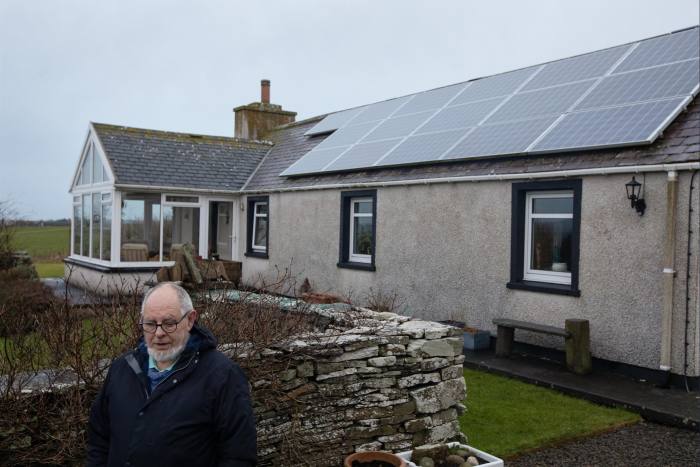 man in frnt of his house that has solar panels on the roof