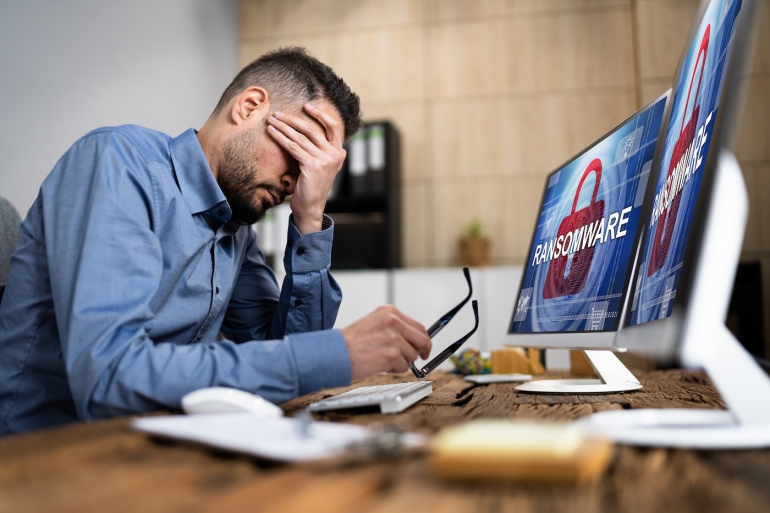 Ransomware on a screen and a person with his head in his hands.