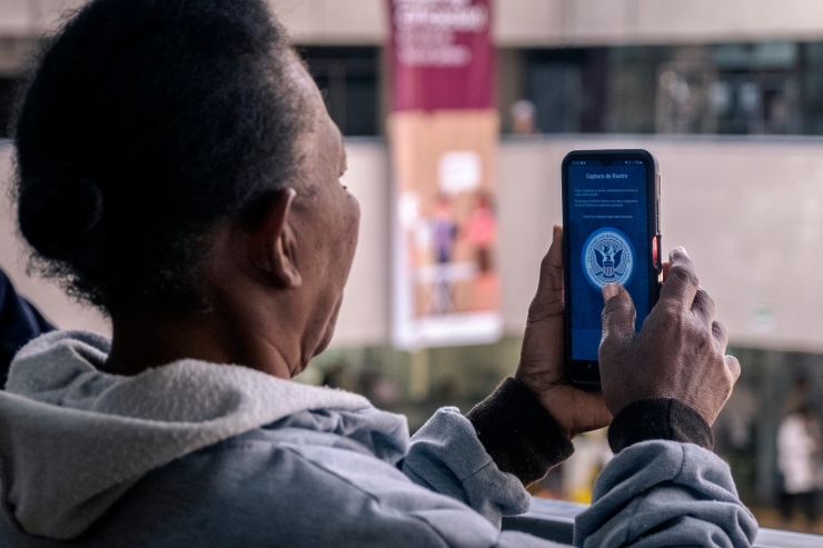 A Black woman holds her phone up to her face to take a self portrait photo. 