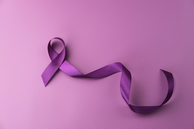 Purple ribbon as symbol of World Cancer Day over purple color background.