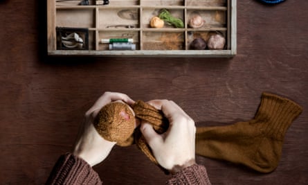 Hands darning sock over desk