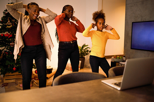 Three people dancing in front of a laptop to make a Tiktok video