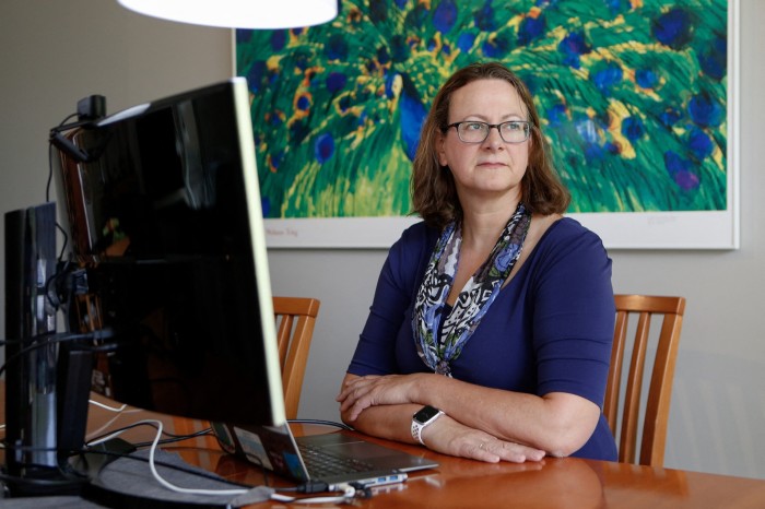 Elisabeth Bik sits at her computer in front of a painting of a peacock