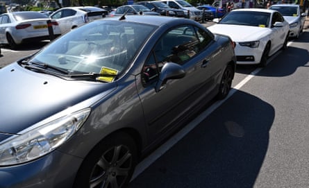 Yellow parking tickets are pictured on the windscreens of cars in a car park near the beach in Bournemouth, England, in June 2020