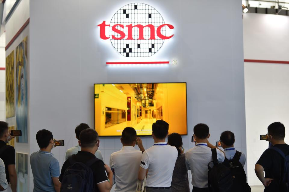 A group of people looking at TV screen with logo of Taiwanese chipmaker TSMC above.