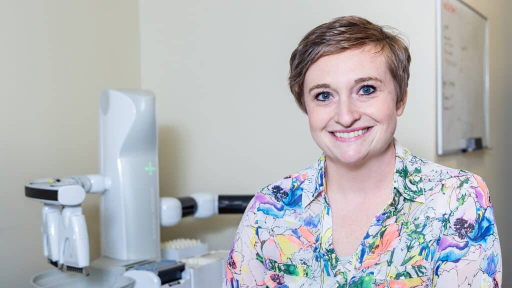 Stefanie Andersen stands for a portrait in front of lab machinery.