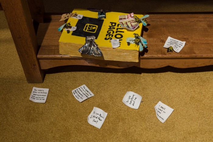 A ceramic Yellow Pages covered in ceramic flies with ceramic postit notes