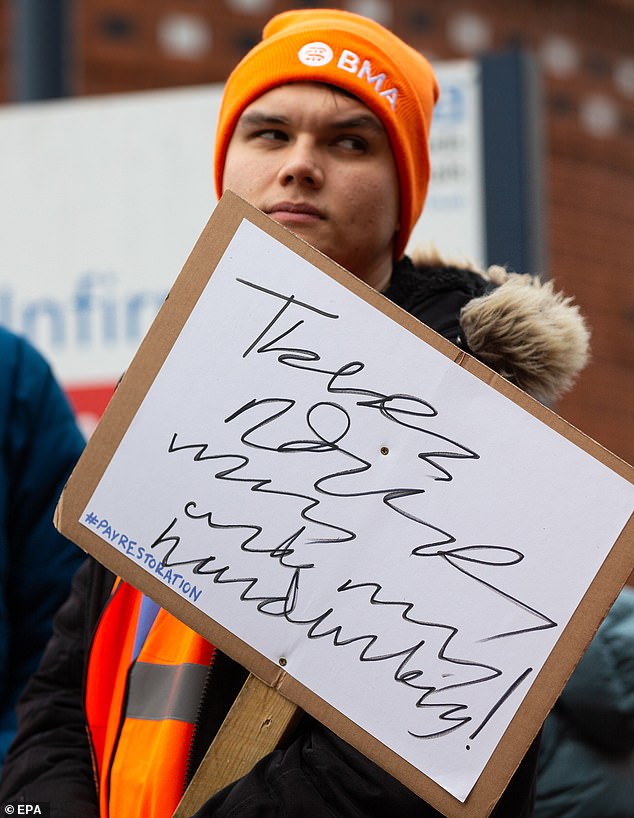 A striking junior doctor holds up a sign outside Leeds General Infirmary in Leeds, Britain, March 13 2023