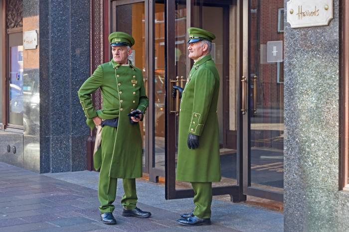 Uniformed doormen resting from their duties at the entrance to Harrods department store