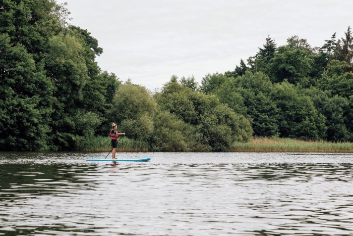 A person paddleboarding on a lake surrounded by trees