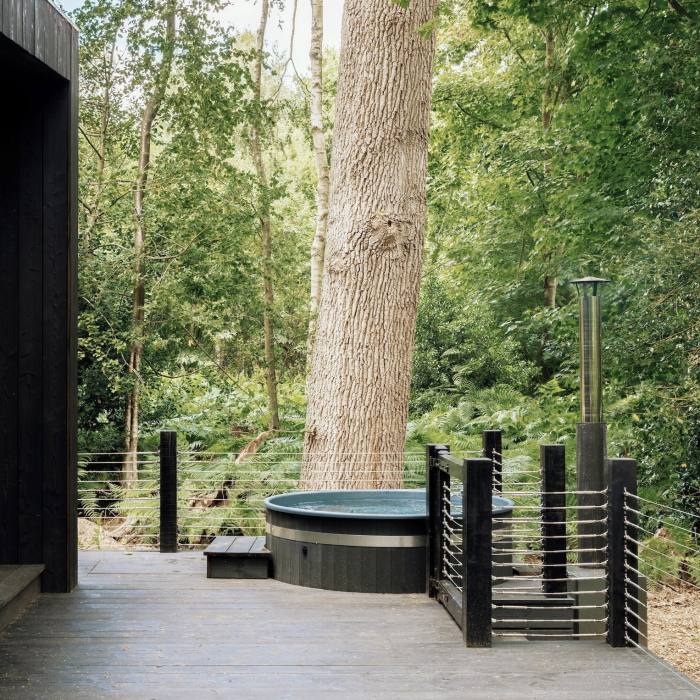 A hot tub on the desk of a cabin in the woods