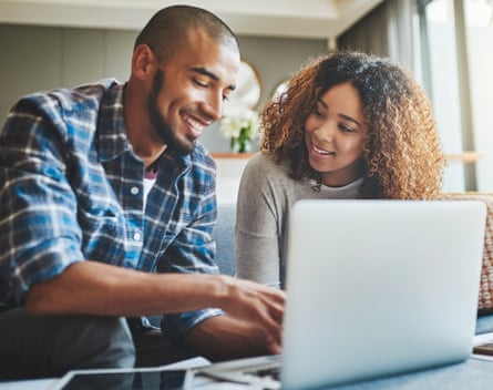 A young couple use a laptop at home