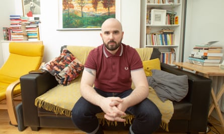 Michael Magee sitting on the sofa in his rented house in Belfast. 