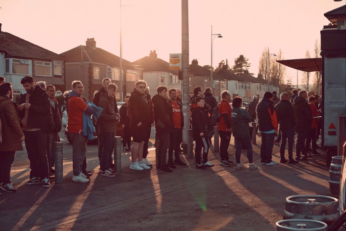 Football fans queue at a food van on match day 