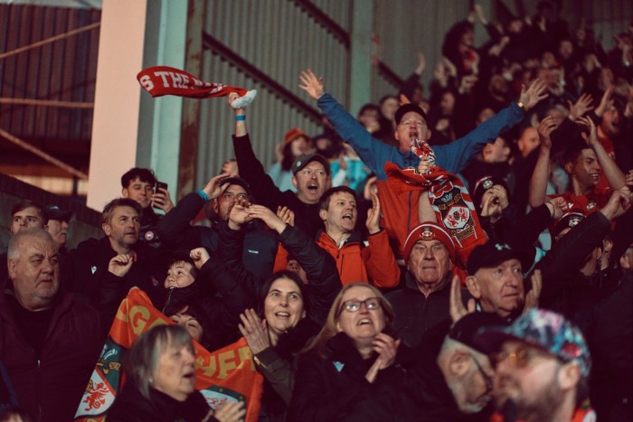 Fans jump up to celebrate a goal in the stands 