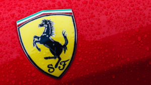 A close-up of the Ferrari logo on a red car with drops of water