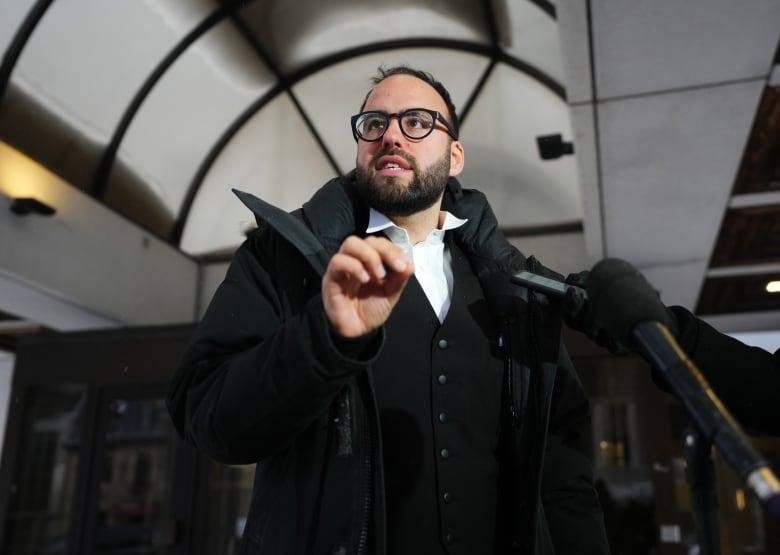 A lawyer speaks to reporters outside the door of a courthouse.