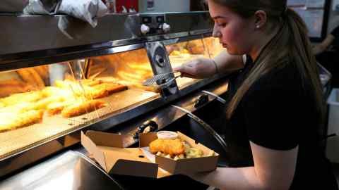 A worker prepares a portion of fish and chips at Eaton Place Fish Bar
