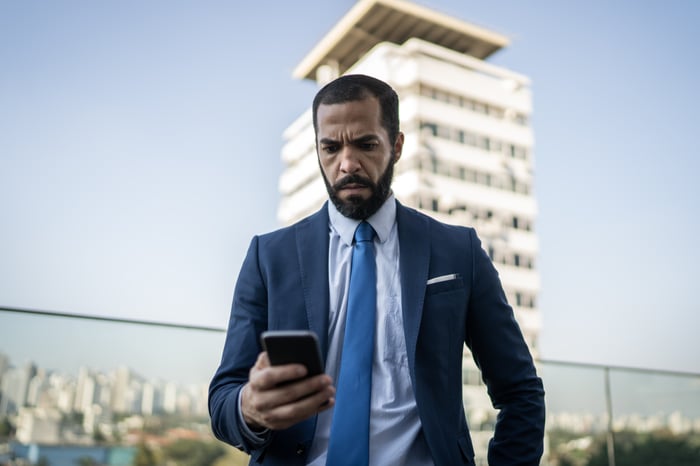 Investor in suit looking at smartphone.