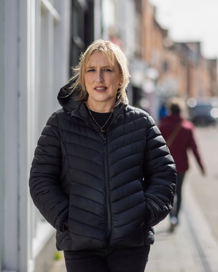 Helen Lord photographed on the street, on a narrow pavement, wearing a padded anorak