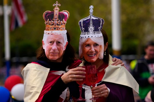 Two people pose wearing King Charles III and Camilla, the Queen Consort masks in London, Friday, May 5, 2023. King Charles III will be crowned King at Westminster Abbey on Saturday May, 6. (AP Photo/Petr Josek )