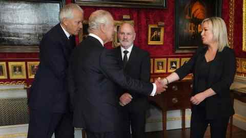 King Charles shakes hands with a Northern Ireland politican while two others look on