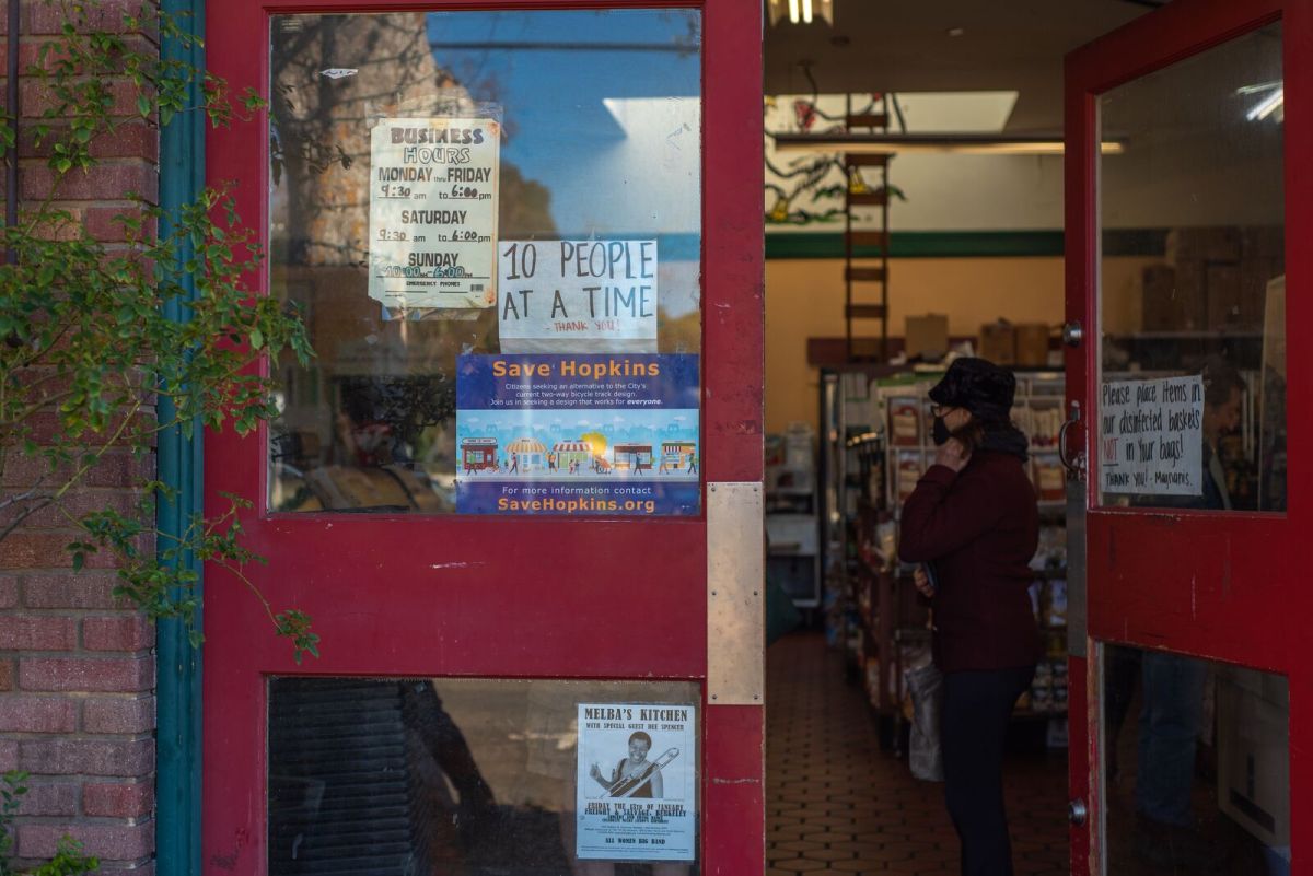 The entryway of Magnani Poultry displays a "Save Hopkins" sign while shoppers wait inside.