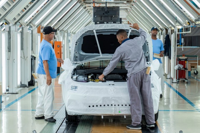 Employees work on manufacturing a car at a Volkswagen plant