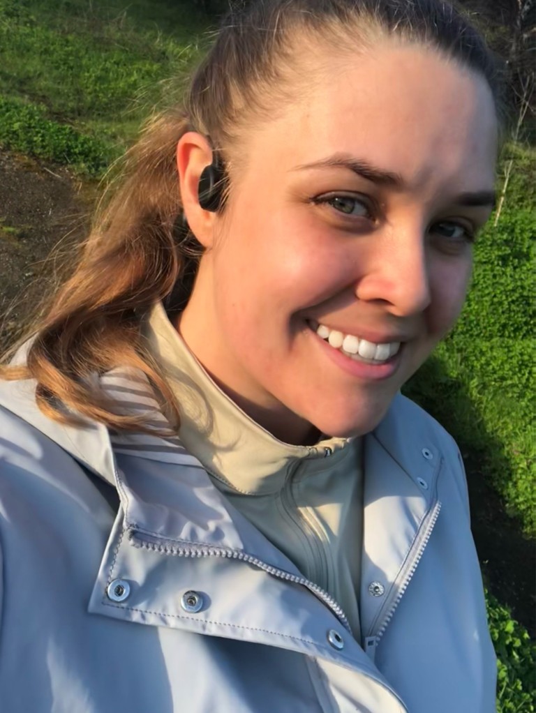 Emma Rossiter, a young woman with dark hair, smiles while on a run, wearing a blue jacket