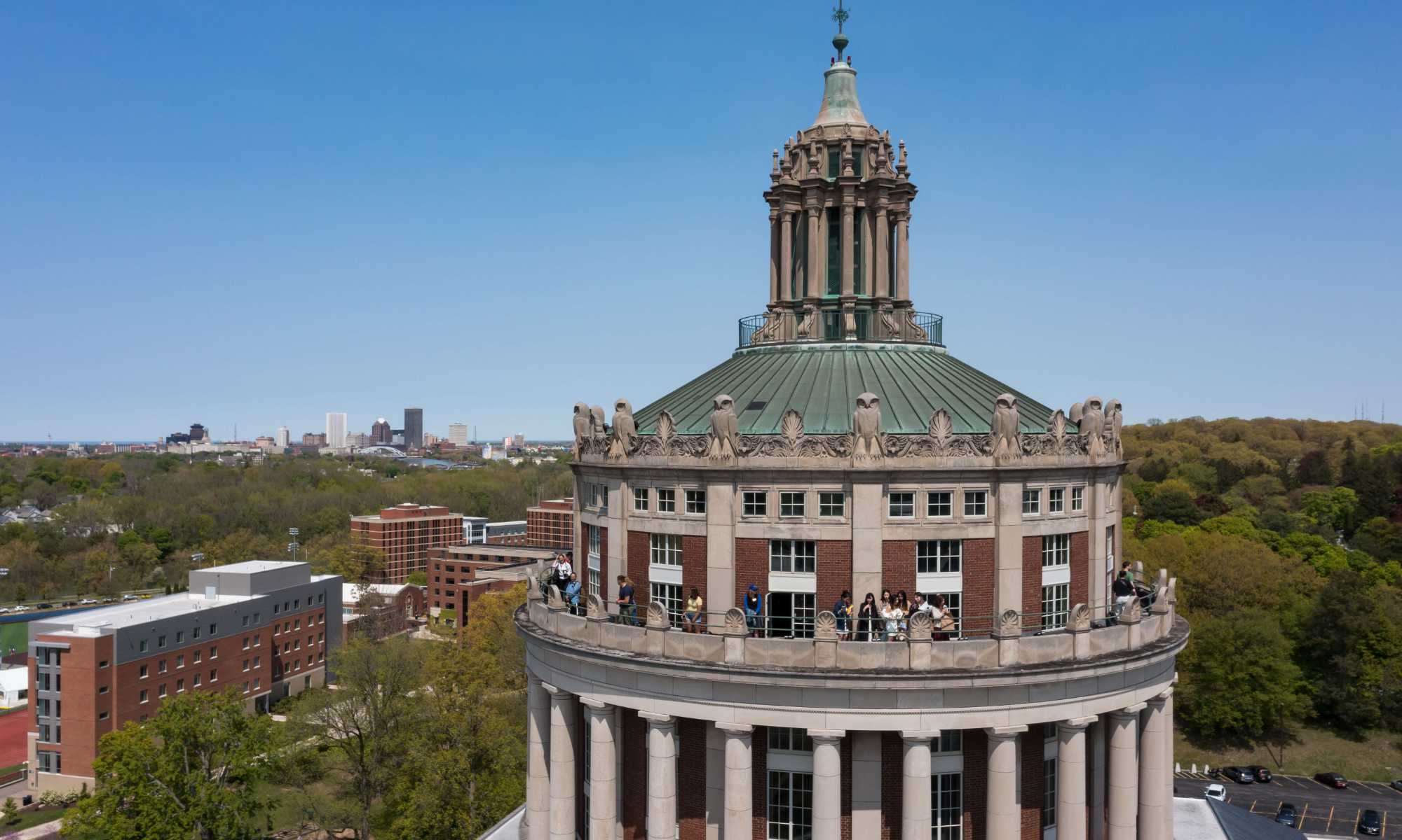 Drone photo of the Rush Rhees Library tower with the City of Rochester skyline in the background.