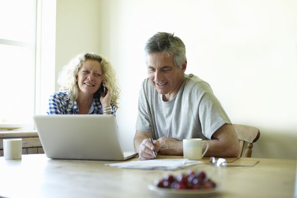 Couple sitting at table using laptop and phone