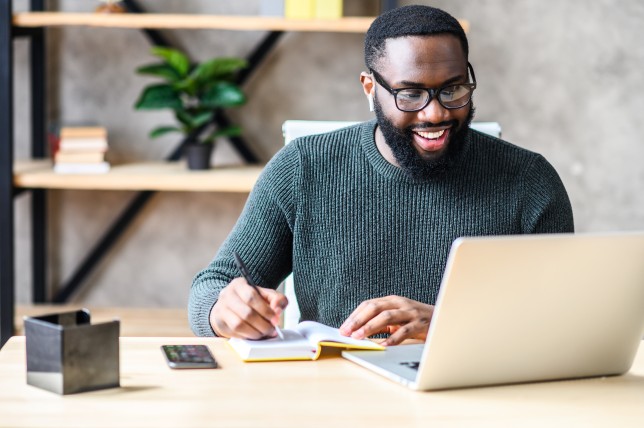 Man smiles as he uses his laptop