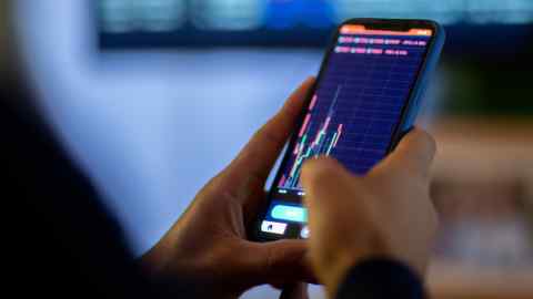 Man looking at currency trading app on his smart phone