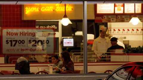 A ‘Now hiring’ sign is displayed on the window of a fast food restaurant in Encinitas, California