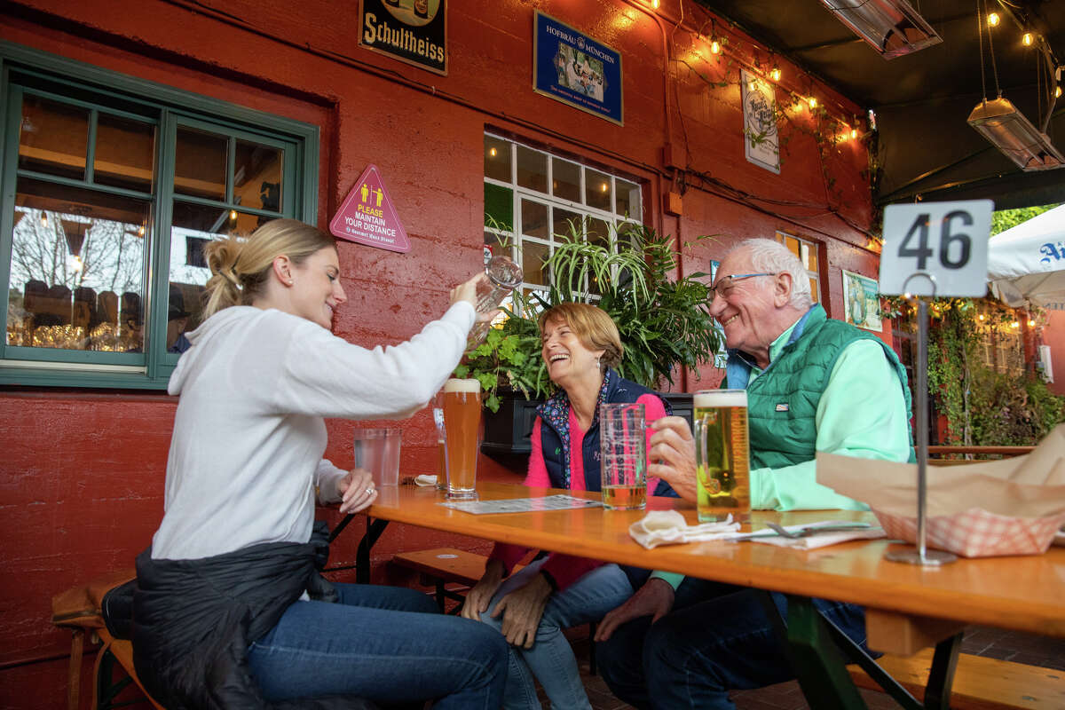 (Left to right) Diana Mandl drinks a beer with her parents Gabirella and Michael Mandl in the beer garden at Gourmet Haus Staudt in Redwood Calif., on January 14, 2022.